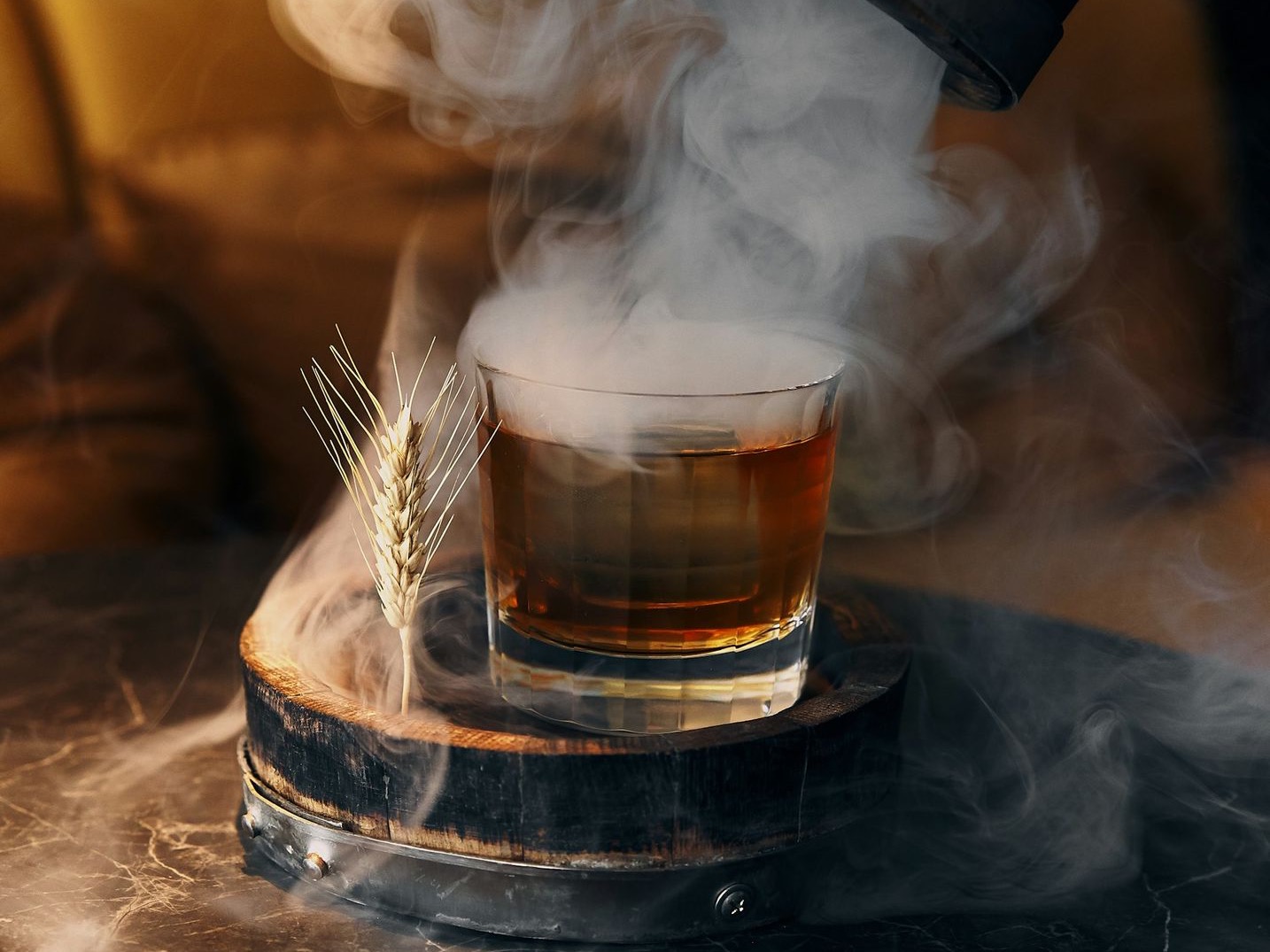 person pouring brown liquid on clear glass container