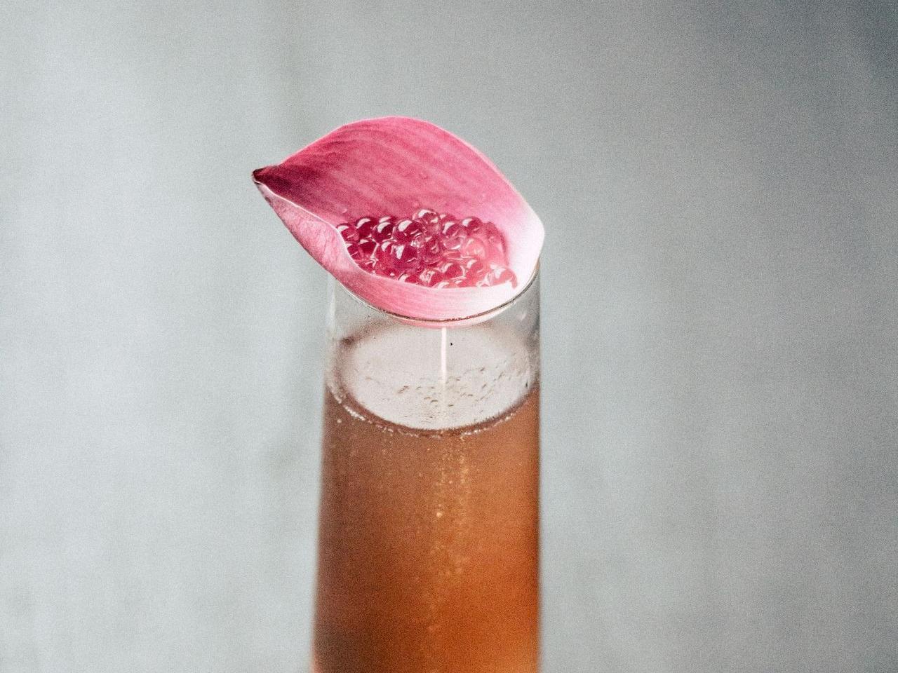 beverage in glass with pink leaf on top