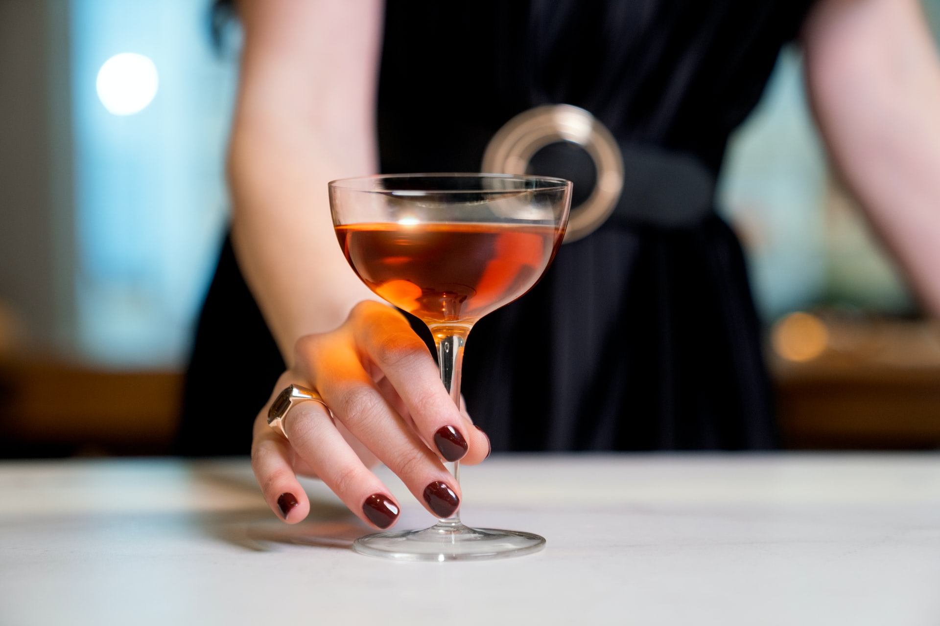 a woman's hand holding a wine glass with a drink in it